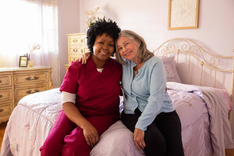 Member and clinician sitting on a bed with arms around each other